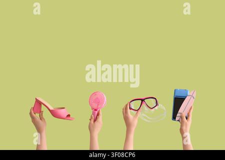 Hands holding summer and travel items on green background Stock Photo