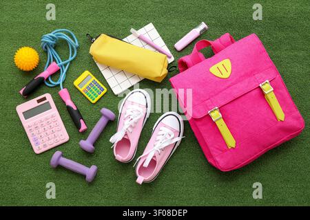 Composition with backpack, school supplies and sports equipment on green grass background Stock Photo
