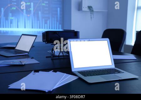 Interior of data scientists office with workplace, laptops, documents and diagrams projection on wall Stock Photo