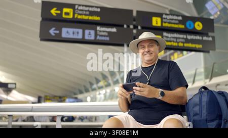 Man traveling, waiting in airport terminal, using smartphone Stock Photo