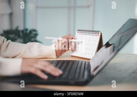 Person using pen for calendar planning to circle event time, scheduling business meeting and medical checkup appointment while writing schedule on des Stock Photo