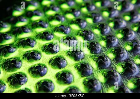 Abstract view of a metal kitchen grater surface glowing with vibrant green led light Stock Photo