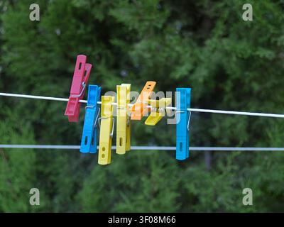Close-up of a row of brightly colored plastic clothespins on a garden clothesline for naturally drying clothes. An eco-friendly and sustainable method Stock Photo