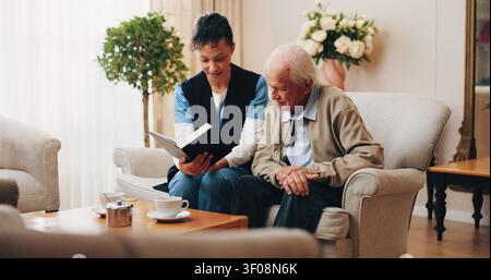 Nurse, elderly and reading with bible for faith, religion or belief together in nursing home. People, caregiver or senior care with holy book for Stock Photo