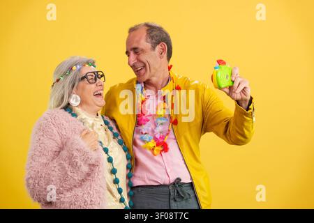 Active mature couple laughing and celebrating with toy camera Stock Photo