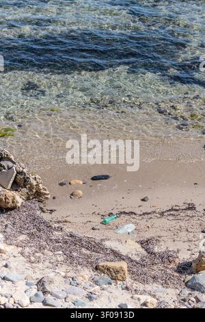 discarded plastic bottle and transparent sea water at beach on Mediterranean coast, shot in bright springtime light Nora beach, Pula, Cagliari, Italy Stock Photo