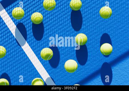 multiple bright green tennis balls scattered on a vibrant blue hard court surface with white lines and crisp shadows under direct sunlight, creating a Stock Photo