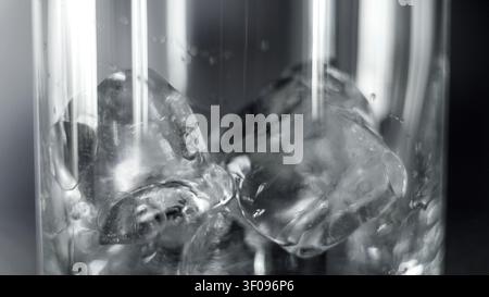 Ice cubes melting in a clear glass, creating a refreshing cold drink, abstract close-up macro view Stock Photo