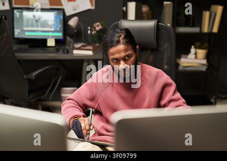 Young Man Editing Video Content in Creative Office Stock Photo