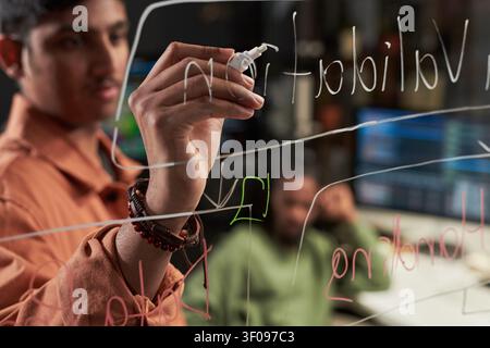Young Man Writing on Glass for Innovation Planning Session Stock Photo