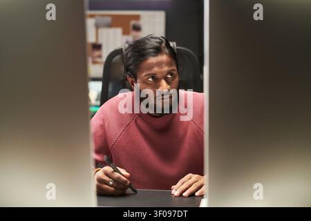 Indian Man Using Stylus While Working on Digital Design Project Stock Photo