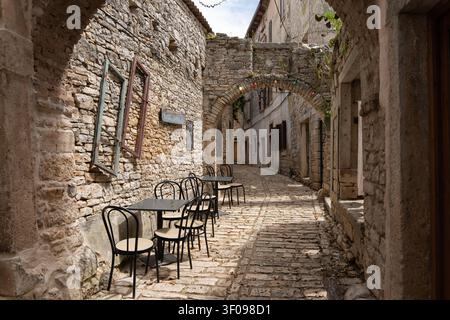 serene cobblestone alleyway with empty seating area in historical stone buildings, first-person perspective from the alleyway, inviting and nostalgic Stock Photo