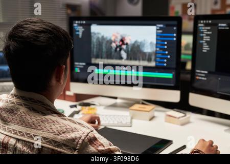 Man Editing Video Content on Desktop for Media Production Stock Photo