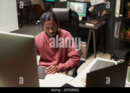 Indian Man Working at Computer in Creative Office Stock Photo