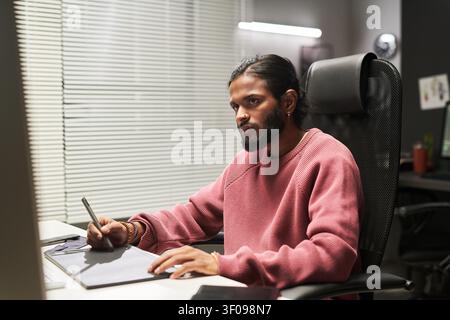 Indian Man Using Graphic Tablet for Creative Work Stock Photo