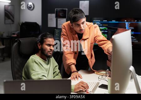 Men Reviewing Software Code on Desktop in Office Stock Photo