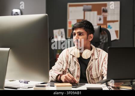 Asian Man Using Computer for Digital Design Work Stock Photo