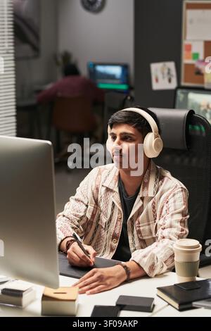 Asian Man Editing Video at Computer in Creative Office Stock Photo