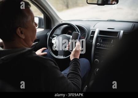 Senior man using smartphone while sitting in parked car Stock Photo