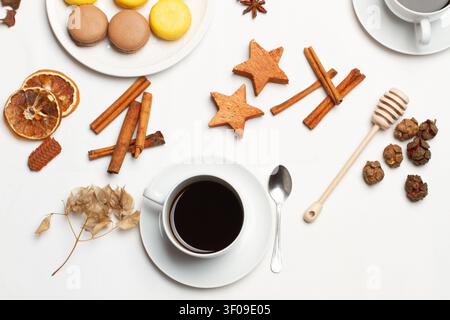 A cup of coffee, macarons and dried orange slices on a decorated table Stock Photo