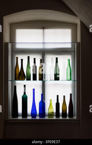 Collection of vintage glass bottles displayed in illuminated museum showcase window Stock Photo