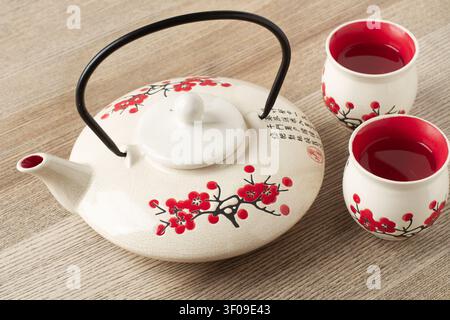 Decorated tea pot with two cups on a wooden table Stock Photo