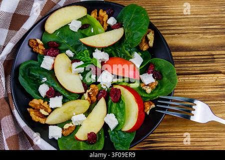 Autumn spinach salad with apple, feta cheese, walnut and dried cranberry on wooden table. Top view. Healthy vegetarian food Stock Photo