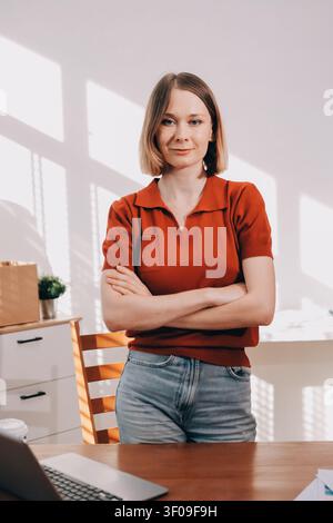 Young woman works on a touchpad, feeling comfortable at cozy home office with a green plant on the background Stock Photo