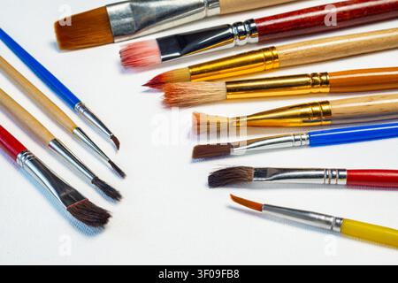 Different paint brushes are placed on a white surface showing their colors and sizes for an artistic activity or project. Stock Photo
