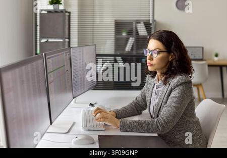Accountant analyzing finance data on multiple monitors in modern office workspace Stock Photo