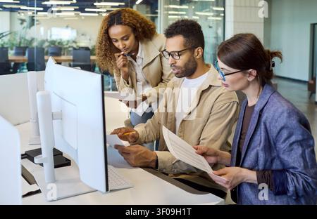 Diverse office team collaborating at computer during meeting planning discussion Stock Photo