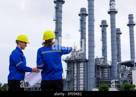 Professional industrial engineers reviewing schematics while inspecting a complex petroleum refining plant. Stock Photo