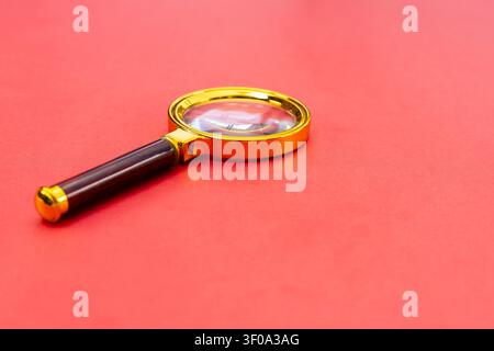 Close Up of Gold Magnifying Glass on Red Background with Selective Focus and Copy Space Stock Photo