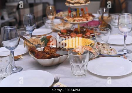 Assorted party food served on white tablecloth during holiday dinner. Many delicious dishes like meat snacks and fresh salads are ready for guests. Go Stock Photo