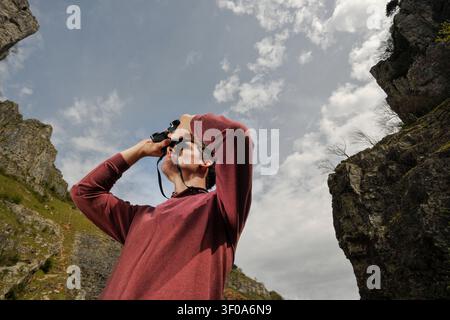 young man looking at mountain view through binoculars Stock Photo