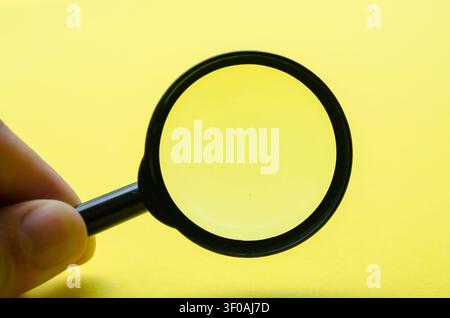 Hand holding magnifying with yellow background and with customizable space for text or ideas Stock Photo