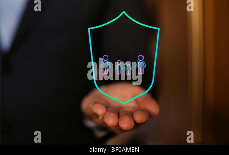 Businessman presents a digital shield icon featuring stylized figures, symbolizing family protection and security in a corporate setting Stock Photo