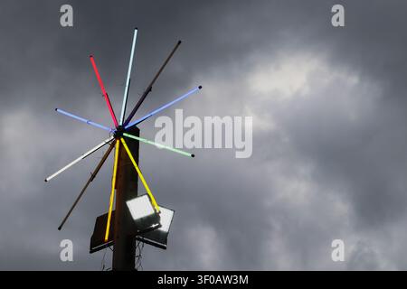 Colorful light installation on rural pole beneath storm clouds with copy space. Dramatic weather scene in an Asian countryside setting. Stock Photo