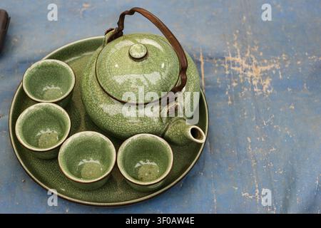 Top view of vintage green ceramic tea set on rustic tray with crackle glaze and copy space. Traditional Asian tea service. Stock Photo