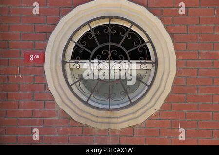 Circular Window and House Number on a Brick Wall Stock Photo