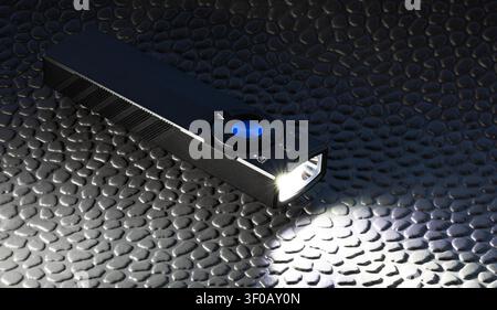 LED flashlight that is rectangular in shape that has a rechargeable battery and rotary switch on a black rubber worm mat. Stock Photo