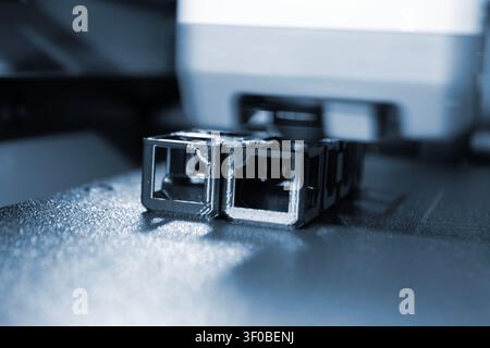3D printer printing black model. Object printed on 3D printer from molten plastic black color. 3D printed object made from molten black plastic. Additive modern manufacturing. 3D printing technology Stock Photo