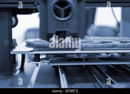 3D printer printing blue model. Object printed on 3D printer from molten plastic blue color. 3D printed object made from molten blue plastic. Additive modern manufacturing. 3D printing technology Stock Photo