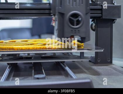 3D printer printing yellow model. Object printed on 3D printer from molten plastic yellow color. 3D printed object made from molten plastic. Additive modern manufacturing. 3D printing technology Stock Photo