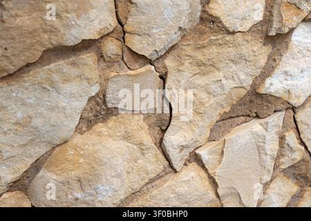 Detailed view of a natural stone wall construction, showcasing the varied shapes and earthy tones of the rocks and the surrounding cement Stock Photo
