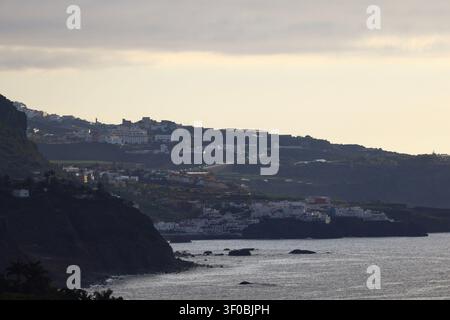 Dramatic sun rays streaming through clouds over the rugged coastline and coastal villages of Tenerife, Canary Islands. Stock Photo