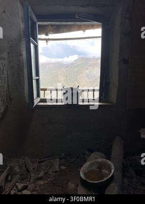 Old enamel kettle on a windowsill overlooking the Caucasus Mountains in the abandoned mountain village of Gamsutl, Dagestan, Russia Stock Photo