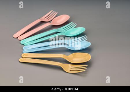 Colorful assortment of pastel plastic cutlery featuring disposable forks and spoons in soft pink, mint green, light blue, and pale yellow shades neatl Stock Photo
