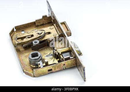 Macro photograph of an old disassembled mortise door lock mechanism revealing complex internal brass components including springs, cam levers, latch b Stock Photo