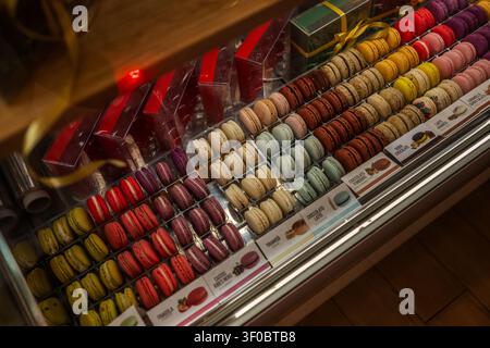 French macarons are arranged by flavor in a glass pastry case Stock Photo